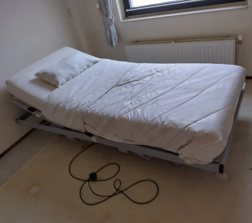 Een oude eenpersoonsmatras op een bedbodem, klaar om opgehaald te worden